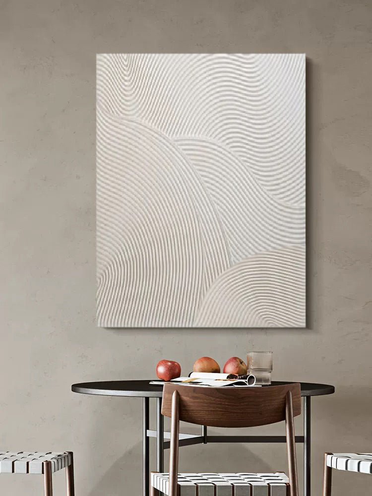 The Abstract Lines Wall Art, a hand-painted piece with wavy patterns, enhances a beige wall above a round table. Featuring four apples and a glass of water, its textured minimalist design perfectly balances simplicity and elegance.