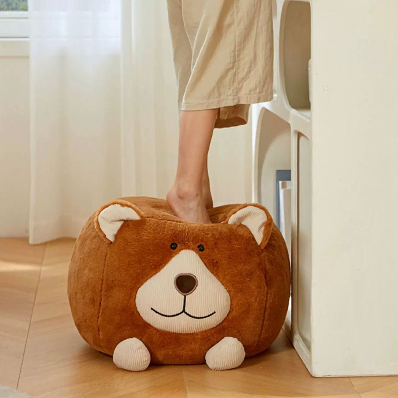 In a charming scene, a person balances on the Adorable Animal Ottoman Stool in the cozy ambiance of a kids' bedroom, where wooden flooring beautifully complements the whimsical bunny or chicken-shaped footrest.