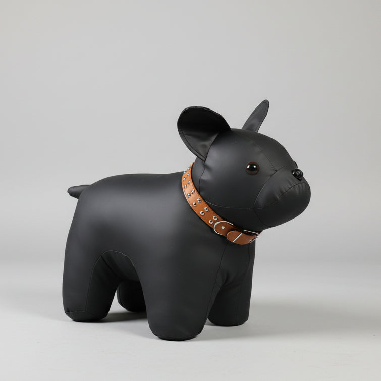 A Cozy Dog Accent Chair door stopper, shaped like a black dog with a studded brown collar, rests against a wooden door on a carpeted floor, creating the perfect backdrop for kids' playtime adventures.