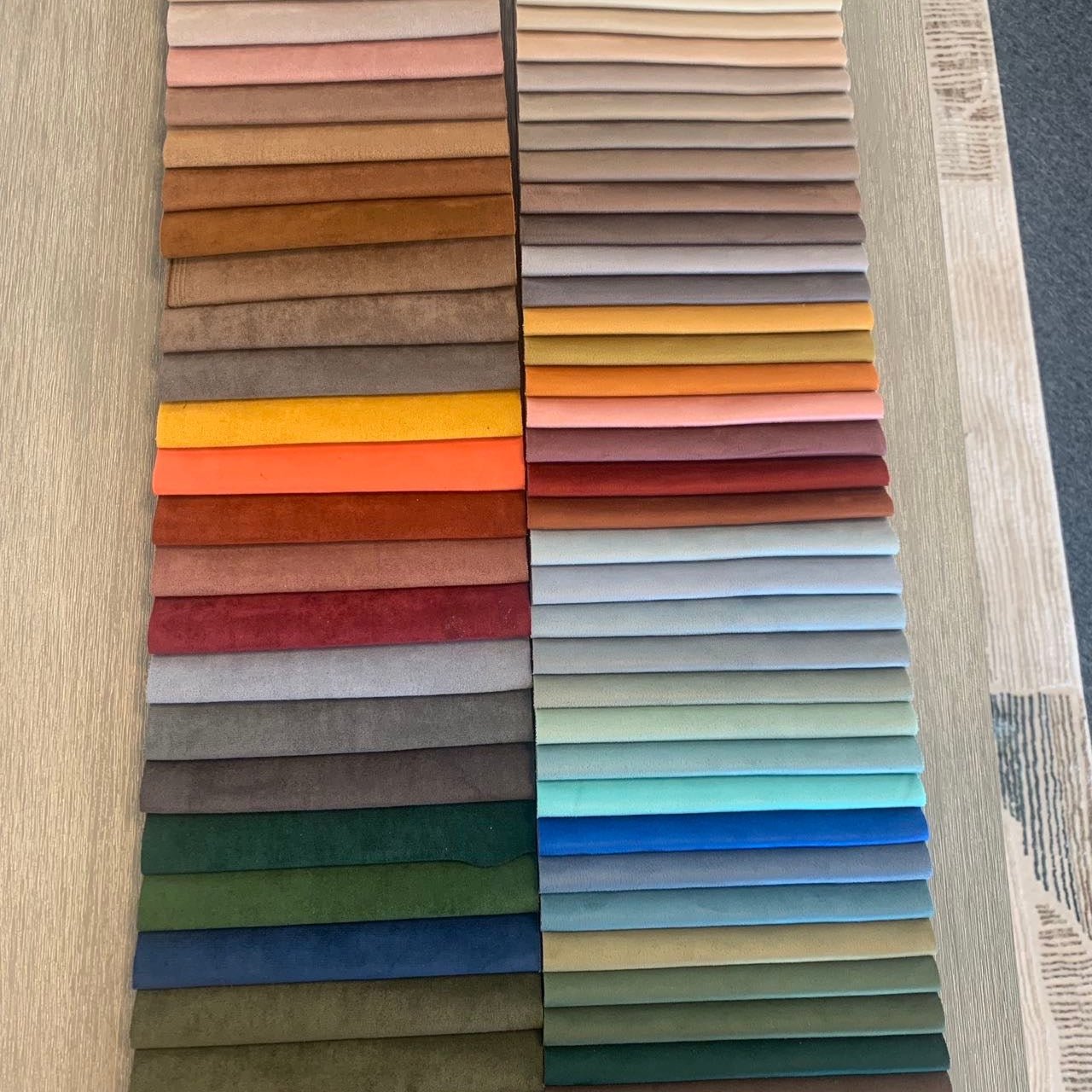 Neatly arranged fabric swatches in hues like brown, red, yellow, blue, and green rest on a light wooden surface—ideal for crafting the Chillax Lounger Sofa Ottoman with its ergonomic design.