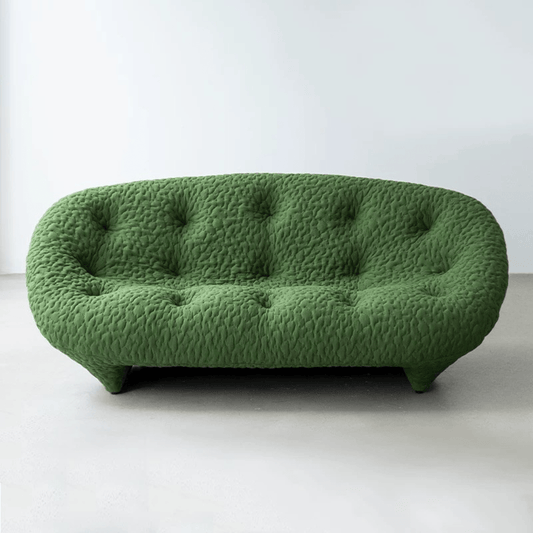 Green Sofa with a rounded design and button-tufted upholstery, set in a minimalist white room.