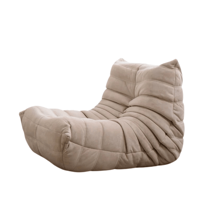 Introducing the Chillax Lounger Sofa Chair: a beige, contemporary chair featuring buttery-soft upholstery and a plush, quilted texture. Its low profile and ergonomic design offer unmatched comfort for relaxation.