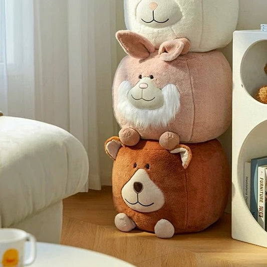 A stack of three Adorable Animal Ottoman Stools sits on the wooden floor, doubling as playful furniture. Nestled near a couch and white bookshelf, these Bunny or Chicken cubes add charm to any kids' bedroom.