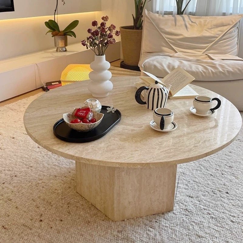 Stone Coffee Table with tea set, snacks on a tray, a vase of flowers, and an open book on a light carpet in a cozy living room.