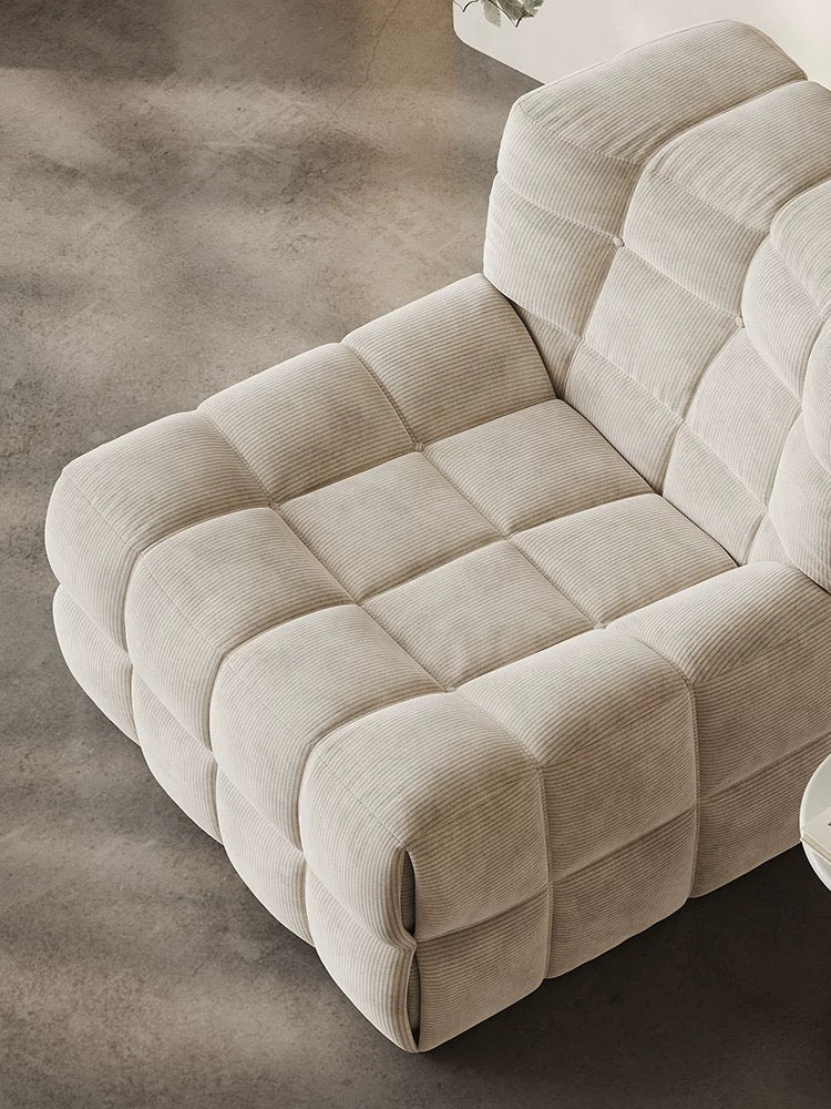 The 休闲椅2, a beige corduroy modular armchair with a quilted, block-like design, is placed on a smooth gray floor.
