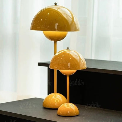 Two yellow Large Bud Table Lamps | Plug-In Edition with Cast Iron Base, each at a different height, are placed on a black surface in front of a white curtain.