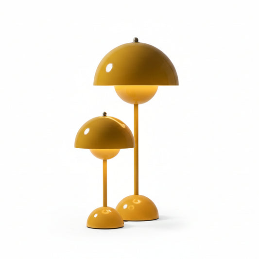 Two yellow Large Bud Table Lamps | Plug-In Edition with Cast Iron Base, each at a different height, are placed on a black surface in front of a white curtain.