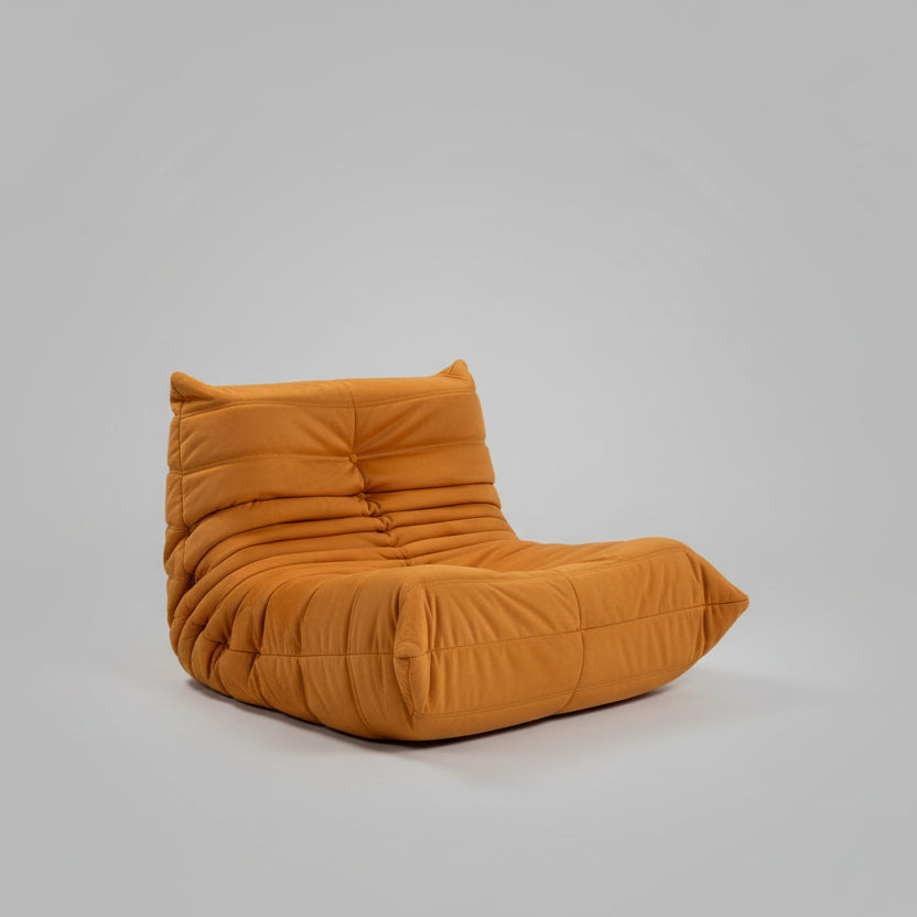 Orange lounge chair in a modern living room with colorful artwork and furniture.