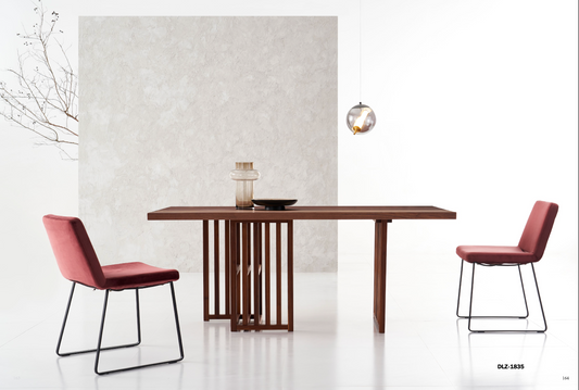 Solid Wood Dining Table adorned with two red chairs. A small branch in a vase and pendant light add charm to the textured wall backdrop.